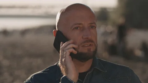 Bald and handsome man in his mid-forties is standing on the beach during a Stock Footage 144382245