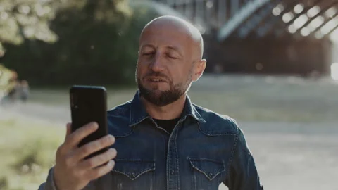 Bald and handsome man with a stylish beard is standing in the park. He is Stock Footage 144382587