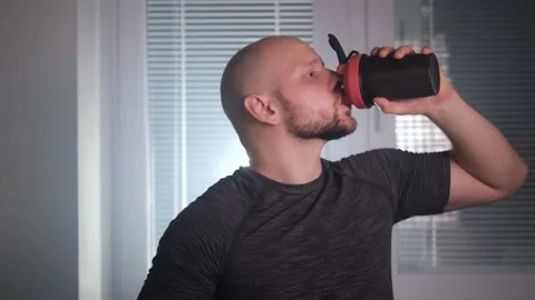 A bald athletic man opens a shaker and drinks sports nutrition Video stock 169050858