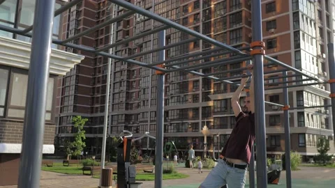 A bald with beard thin skinny guy is engaged on the crossbar on the street. A Stock Footage 205211729