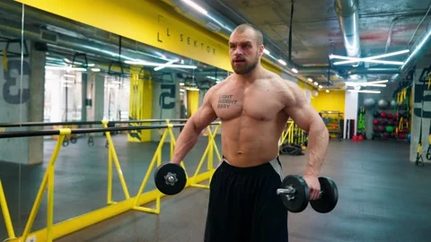 Bald bodybuilder exercising in the gym. Raises the barbell, dumbbells. Stock Footage 238778609