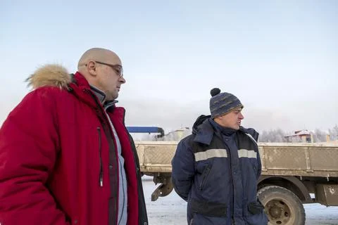 Bald boss in a red down jacket talking to a worker 스톡 사진