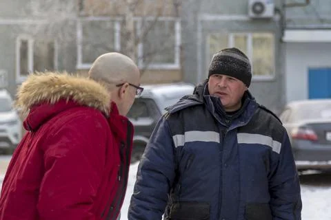 Bald boss in a red down jacket talking to a worker 스톡 사진