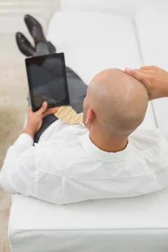 Bald businessman using digital tablet on sofa at home Stock Photos