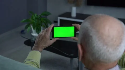 Bald elderly man holding smart phone with green blank screen Stock Footage 216964595