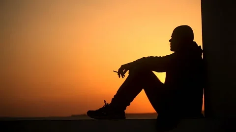 Bald Frustrated guy smokes at sunset by the sea Stock Footage 150250271