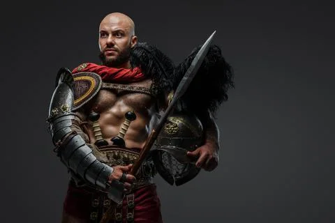 Bald gladiator with naked torso holding spear and helmet Stock Photos