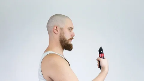 Bald guy with a beard and a clipper in his hands, shaving himself.Thumbs up Stock Footage 122503755