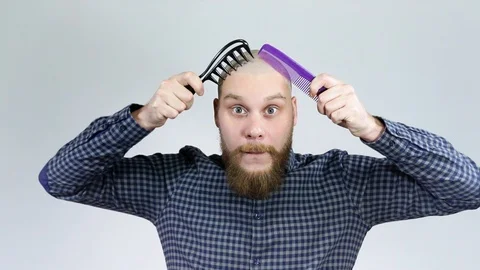 The bald guy combing his bald head with two combs looking at the camera Stock Footage 122005436