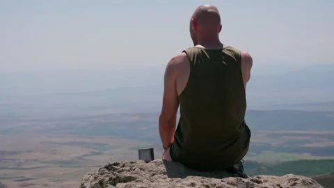Bald guy on the edge of a cliff in the mountains Stock Footage 248872593