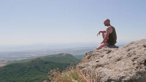 Bald guy on the edge of a cliff in the mountains Stock Footage 248873397