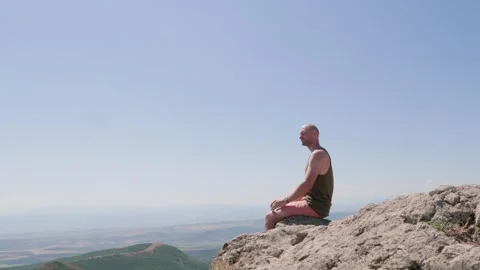 Bald guy on the edge of a cliff in the mountains Stock Footage 248887304