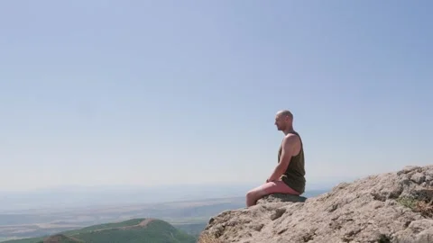 Bald guy on the edge of a cliff in the mountains Stock Footage 248887332