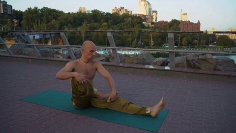 Bald Guy with Naked Torso Doing Yoga Asanas in the Park on the Urban Landscape Stock Footage 85333534
