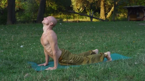 Bald Guy Performs Asanas of Yoga, Engages in Gymnastics on the Glade in the Stock Footage 85822907