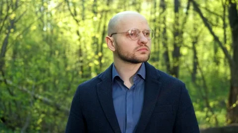 A bald intelligent ecologist man with a beard and glasses looks at the camera Stock-Footage 192353291
