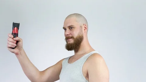 Bald man with a beard holding a clipper and smiling Stock Footage 122503352