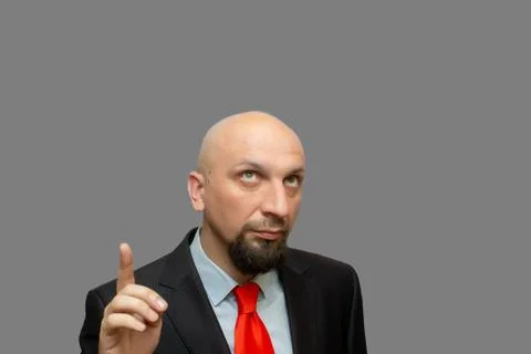 Bald man with beard looking and pointing finger up at grey background Stock Photos