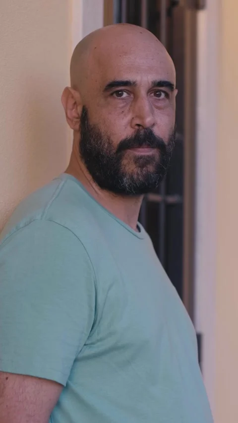Bald man with beard looking down sadly and then at the camera Stock Footage 295141826
