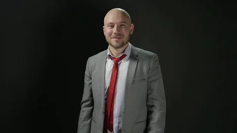 Bald man with a beard in a suit looks at the camera with smiling and Show Big Stock Footage 72106965