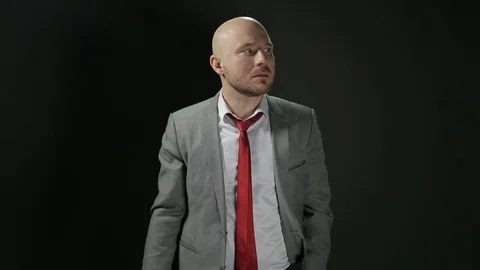 Bald man with a beard in a suit raises his head and looking away with fear in Stock Footage 72106867