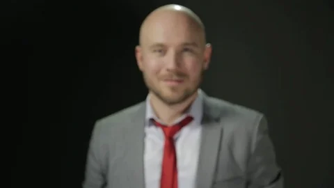 Bald man with a beard in a suit raises his head and looks at the camera with Stock Footage 72107087