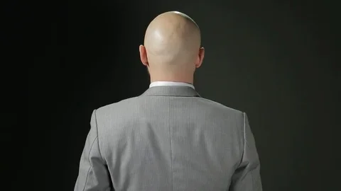 Bald man with a beard in a suit turns to the camera with smiling and Show Big Stock Footage 72108203