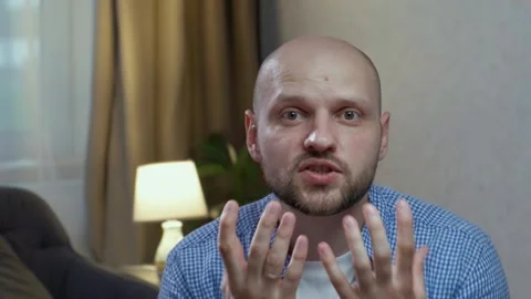 A bald man with a beard swears and waves his arms looking at the camera close-up Stock Footage 242599586