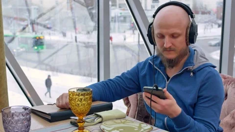 A bald man with a beautifully styled beard and a chic little mustache listens to Stock Footage 153956506