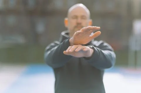 A bald man does an exercise with his hands. the boy does sports. Stock Photos