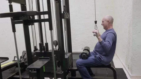 Bald man doing pull ups on black cable machine in bright home gym interior Stock Footage 324755525