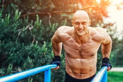 Bald Man doing push ups on parallel bars in a park Stock-Fotos