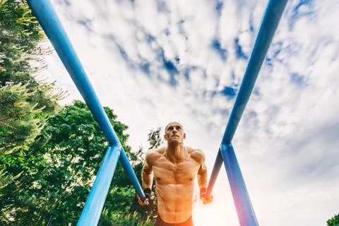 Bald Man doing push ups on parallel bars in a park Foto stock