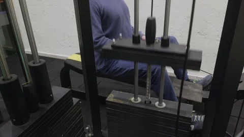 Bald man doing seated cable row exercise on gym machine with weight stack Stock Footage 324755584