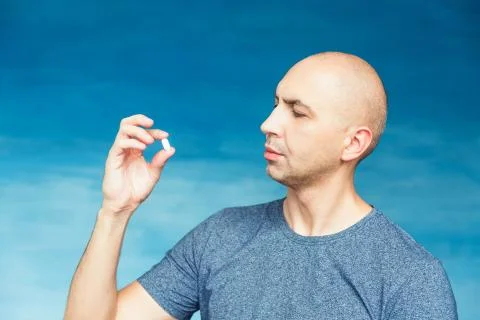 A bald man eats pills with greed. Stock Photos