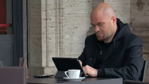 Bald man focused on working with the tablet, sitting in cafe,portrait Stock Footage 74704430