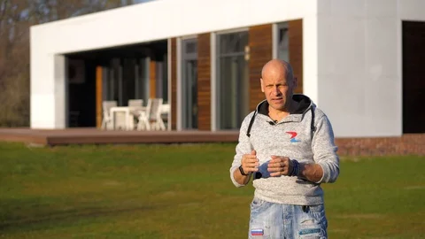 A bald man gives an interview against the background of a house with a terrace Stock Footage 129510391