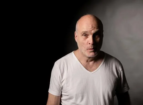 Bald man with intense gaze in dramatic low key lighting Stock Photos