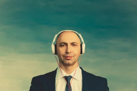 A bald man in a jacket and tie looks peacefully at the camera listens and enj Stock Photos