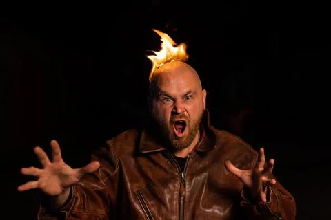 Bald man in a leather jacket with a burning head on a dark background. Stock Photos