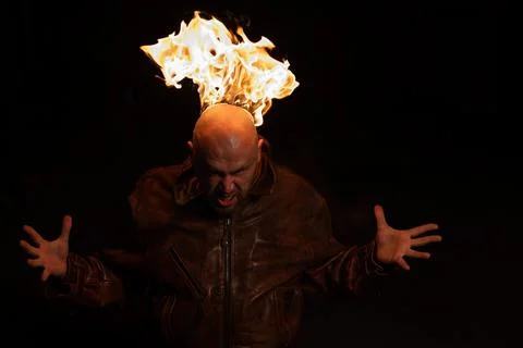 Bald man in a leather jacket with a burning head on a dark background. Stock Photos