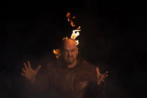 Bald man in a leather jacket with a burning head on a dark background. Stock Photos