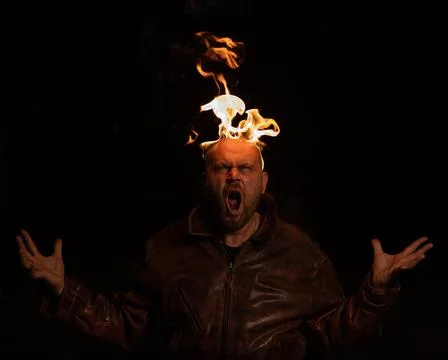 Bald man in a leather jacket with a burning head on a dark background. Stock Photos