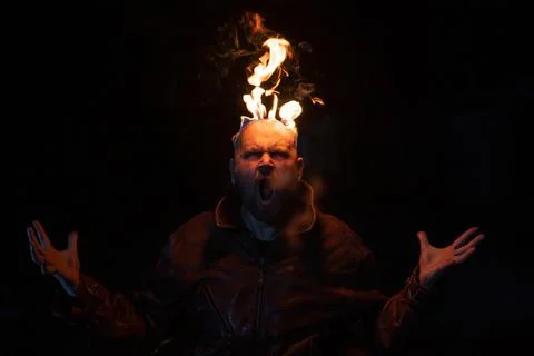 Bald man in a leather jacket with a burning head on a dark background. Stock Photos