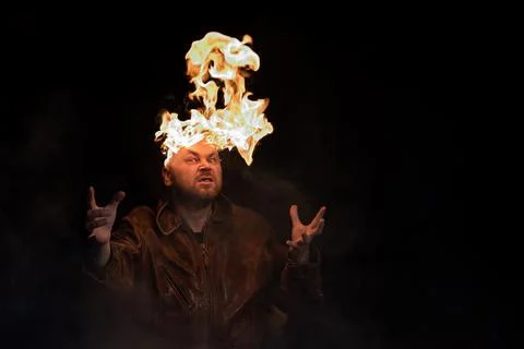 Bald man in a leather jacket with a burning head on a dark background. Stock Photos