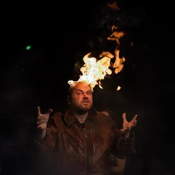 Bald man in a leather jacket with a burning head on a dark background. Stock Photos