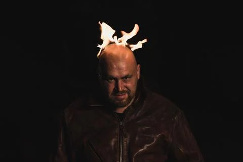 A bald man in a leather jacket with a burning head grins. 스톡 사진