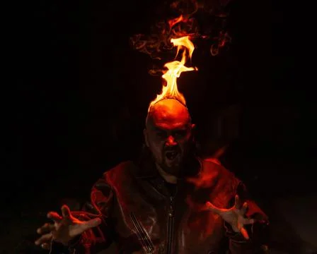 Bald man in a leather jacket with a burning head on a dark background. Stock Photos
