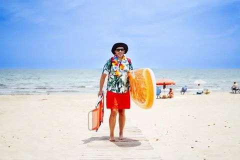 Bald man playing and enjoying his float and mobile, on the beach Stock Photos