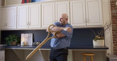 Bald man plays with comically large scissors in an office kitchen Stock Footage 245767334